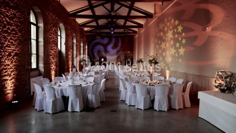 Salle de réception décorée avec des tables rondes dressées, éclairage chaleureux et projections lumineuses sur les murs.
