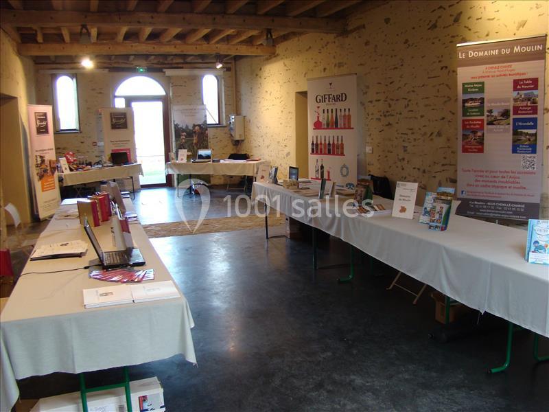 Salle d'exposition avec des stands présentant des produits et brochures, éclairée par une lumière naturelle.