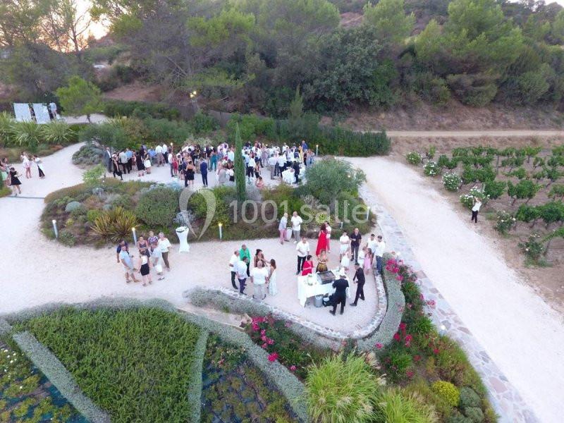 Vue aérienne d'un rassemblement en extérieur dans un jardin entouré de végétation et de chemins.