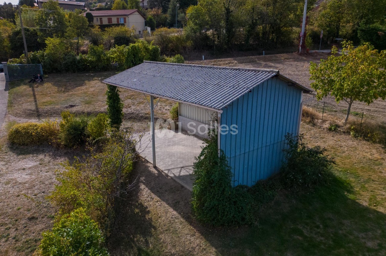 Abri en bois peint en bleu avec toit en tôle, entouré de végétation, situé dans un espace naturel.