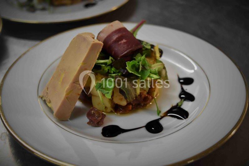 Assiette gastronomique avec foie gras, salade, légumes, viande roulée et décor de sauce balsamique.