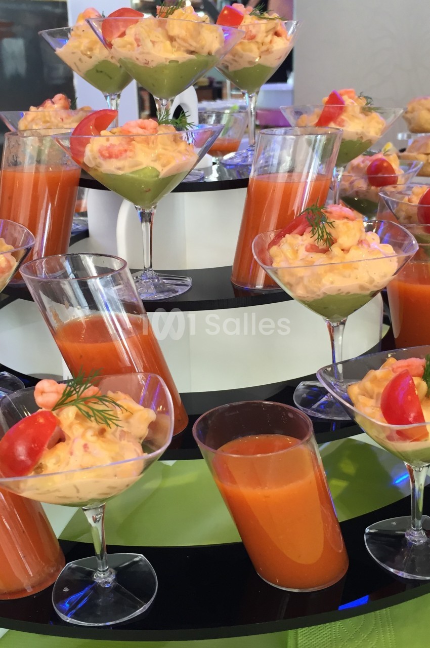 Buffet de verrines colorées avec gaspacho, crevettes, avocat et décorations de tomates et d'aneth.