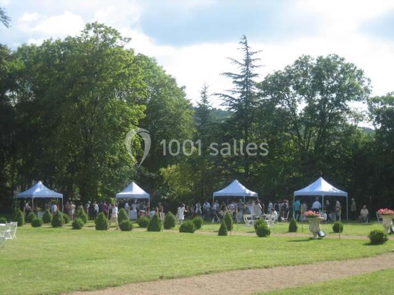 Des tentes blanches installées dans un parc verdoyant, entourées de personnes lors d'un événement en plein air.