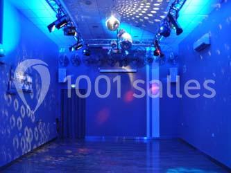 Salle vide éclairée par des lumières colorées et des spots, avec un plafond équipé de projecteurs et une boule disco.