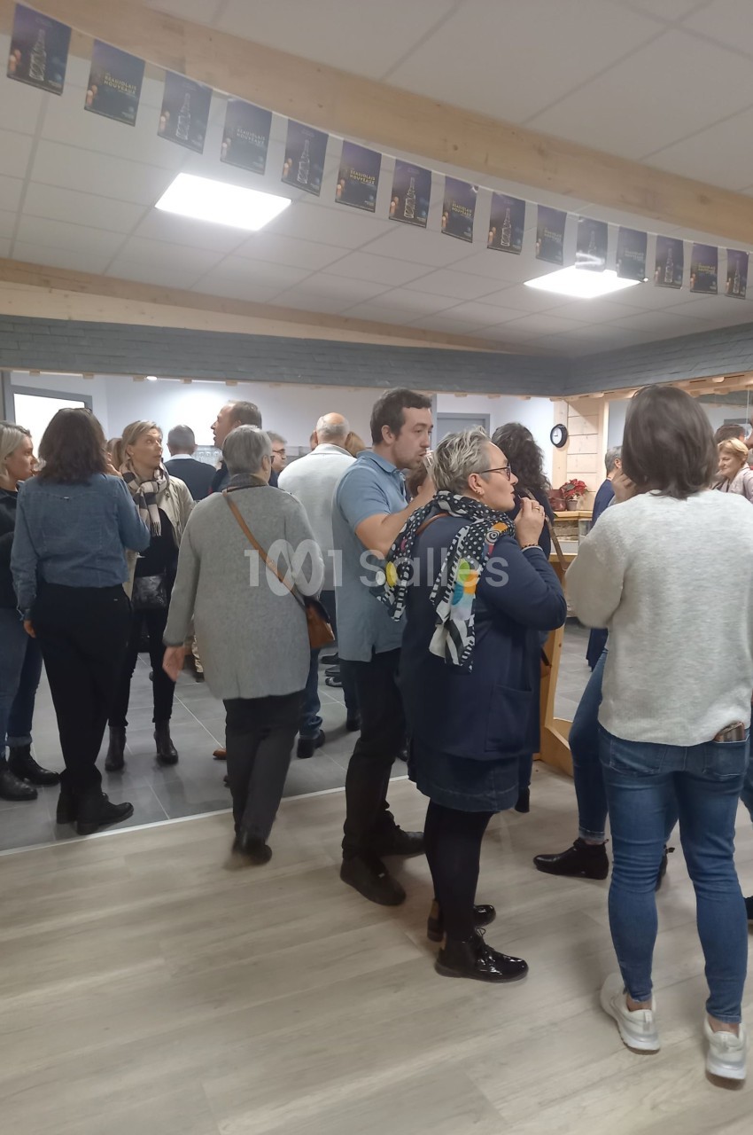 Un groupe de personnes discute dans une salle lumineuse avec un plafond décoré de petites affiches.