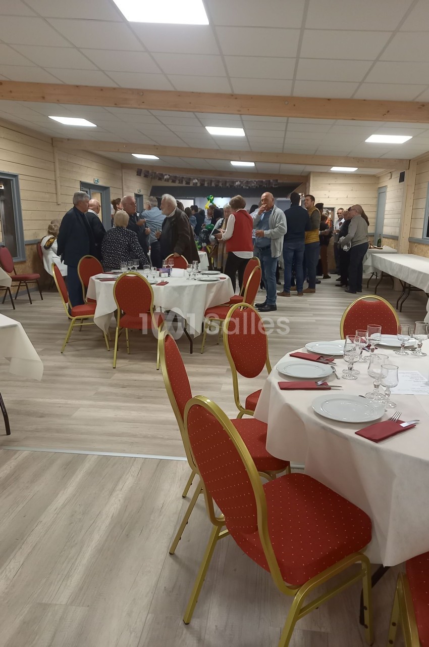 Salle de réception avec des tables dressées et des personnes debout discutant en arrière-plan.