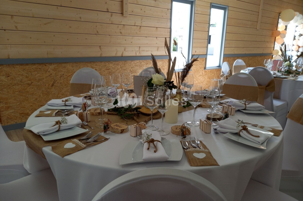 Table de réception décorée avec des éléments naturels, nappes blanches, chemins de table en jute et vaisselle élégante.