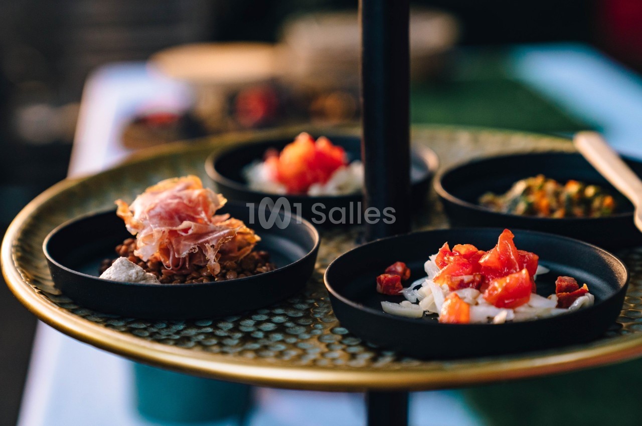 Assortiment de petites assiettes contenant des ingrédients variés comme du jambon, des tomates et des légumes.