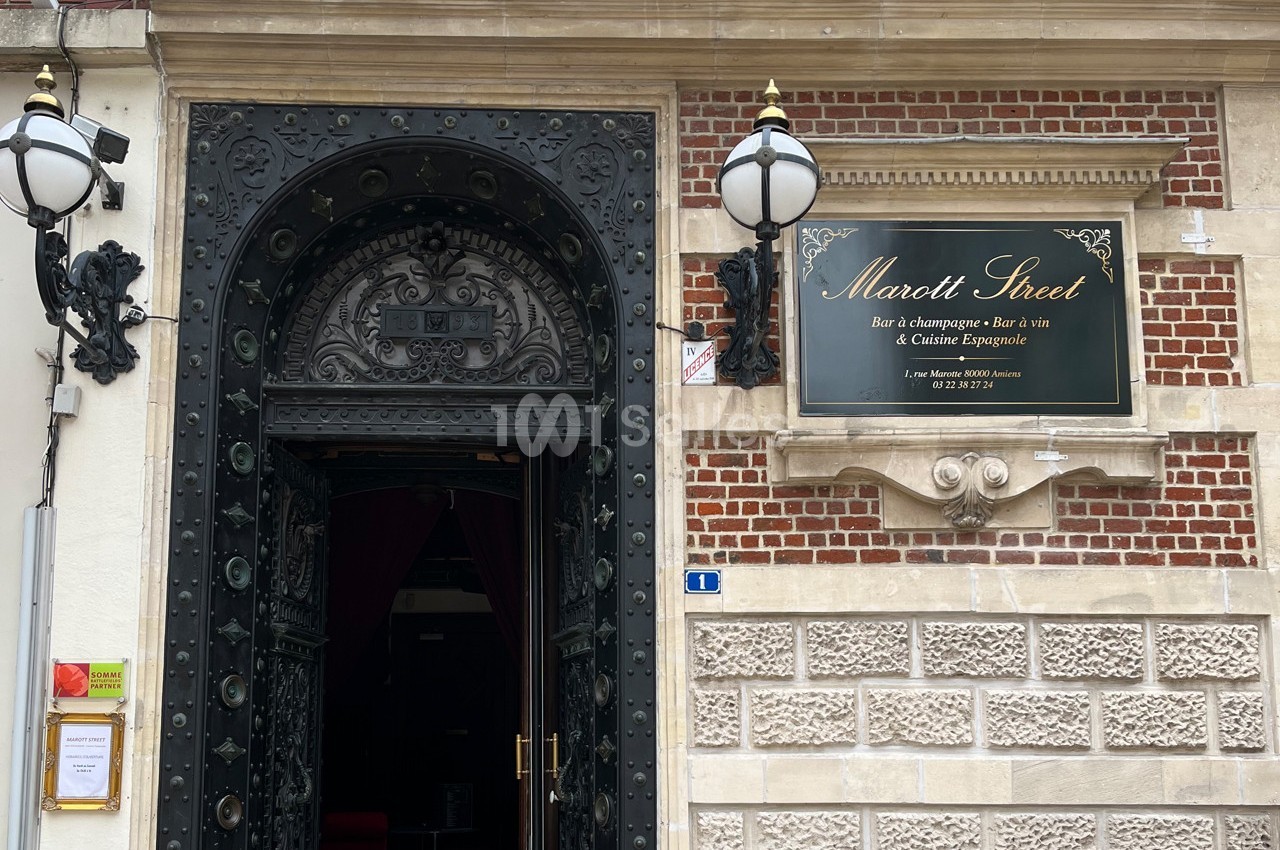 Entrée d'un bar à champagne et à vin avec une porte ornée en métal et une plaque indiquant ’Marott Street’.