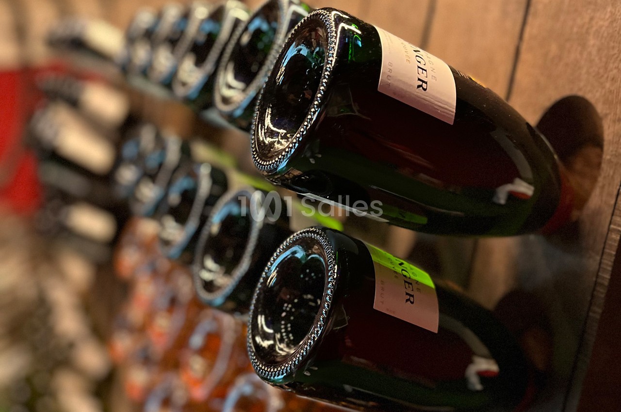 Bouteilles de vin ou de champagne entreposées horizontalement sur un présentoir en bois.