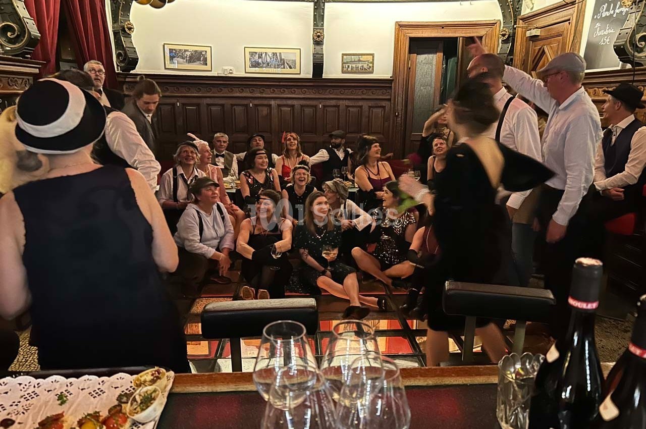 Groupe de personnes en tenue rétro réunies dans une salle élégante, avec des boissons et des décorations festives.