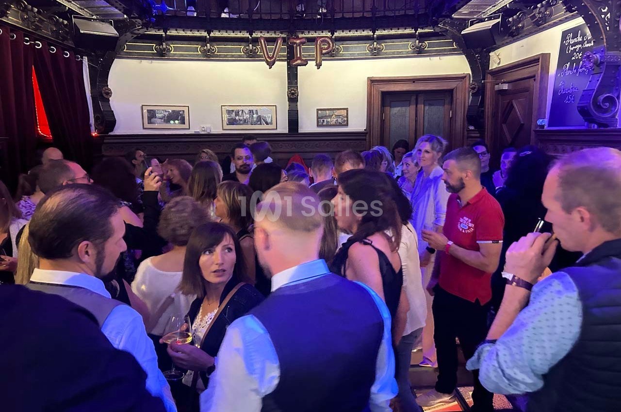 Groupe de personnes discutant dans une salle décorée avec des éléments en bois et une enseigne ’VIP’.
