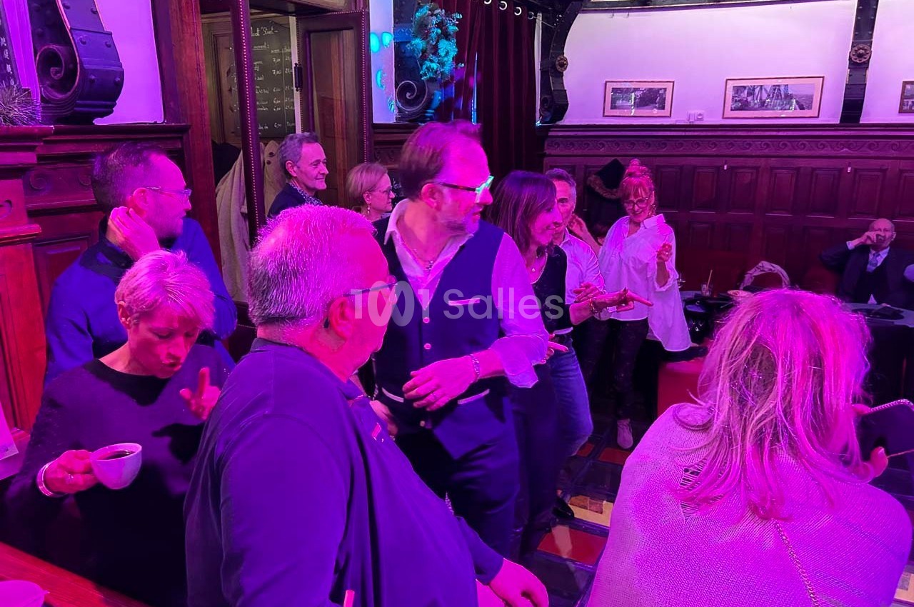 Groupe de personnes discutant et partageant un moment convivial dans un intérieur à l'éclairage coloré.