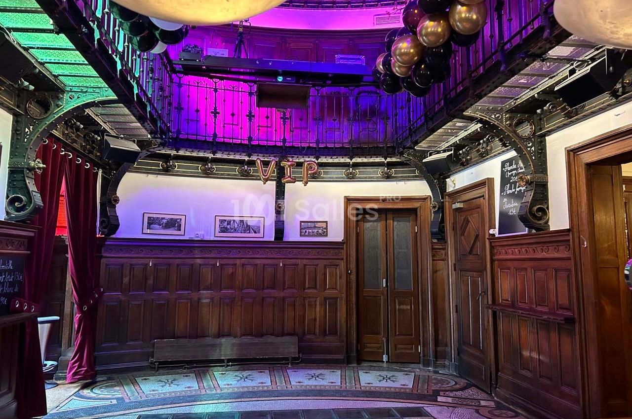 Salle intérieure avec décoration en bois, éclairage coloré, ballons suspendus et inscription ’VIP’ sur le mur.