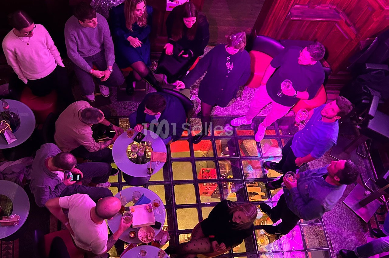 Vue plongeante sur un groupe de personnes discutant et partageant un moment convivial dans un espace éclairé par des…