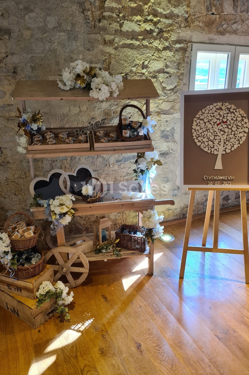 Stand décoratif en bois avec fleurs blanches, accessoires rustiques et tableau d'empreintes en forme d'arbre.