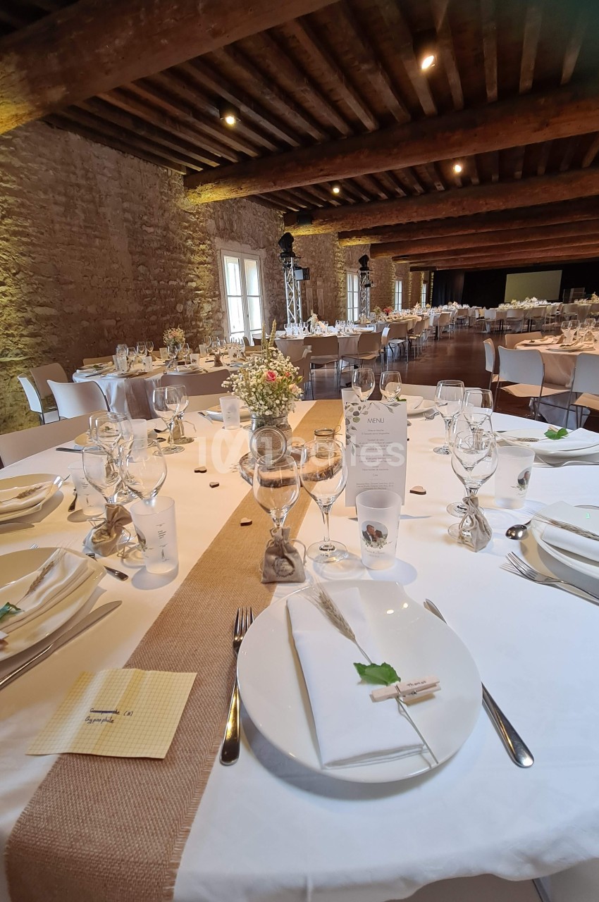 Table élégamment dressée pour un repas, avec nappes blanches, chemins de table en toile de jute et décoration florale.