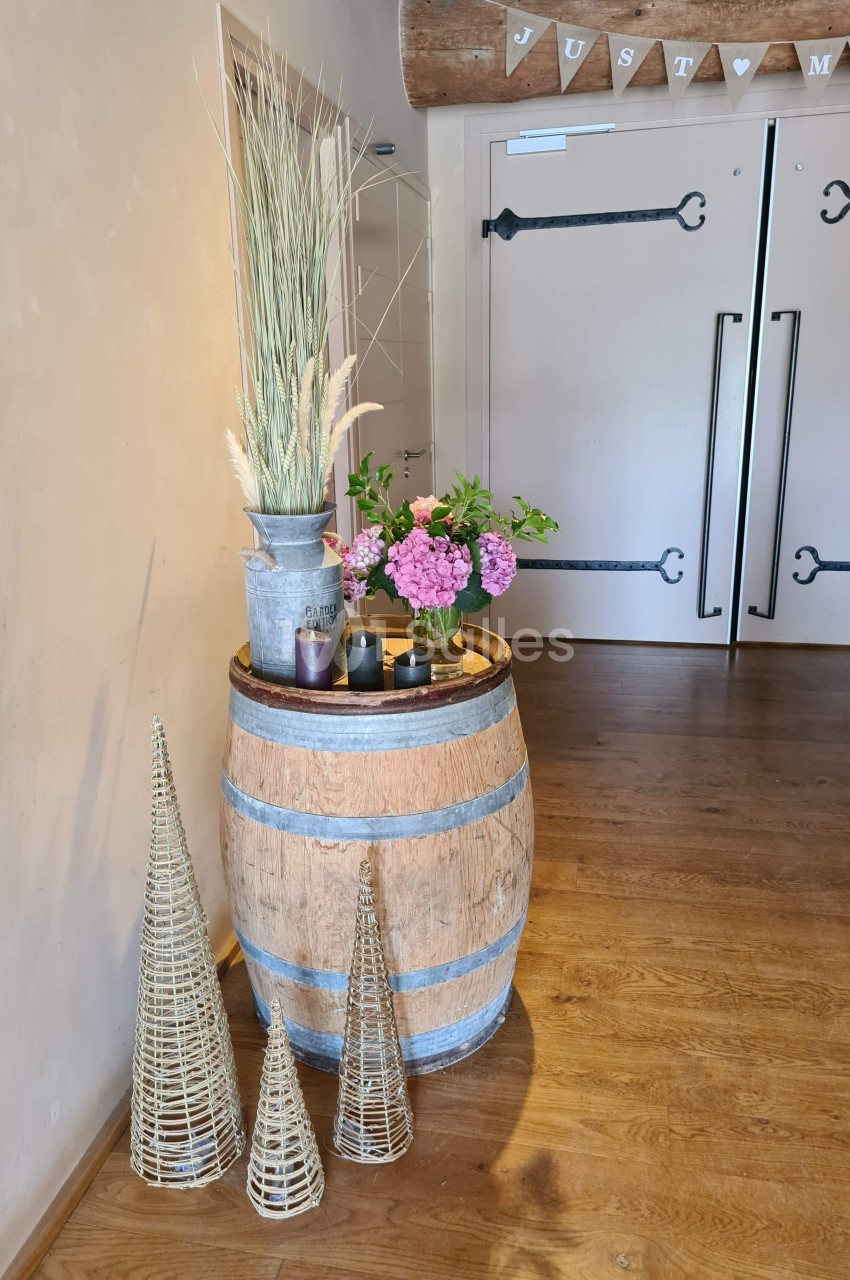Décoration intérieure avec tonneau en bois, fleurs, bougies et ornements en osier devant des portes doubles.