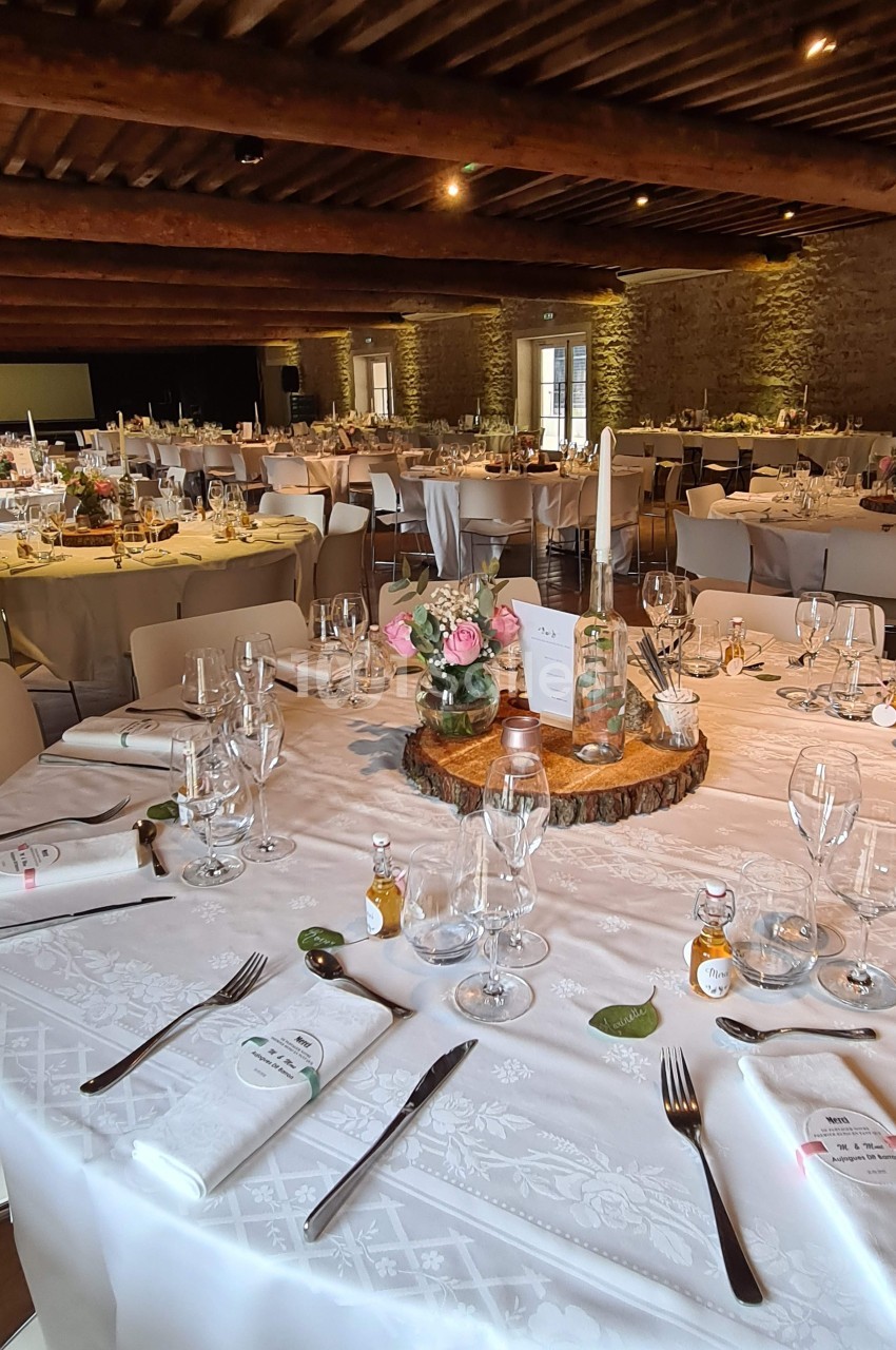 Salle de réception décorée avec des tables rondes élégamment dressées, ornées de centres de table floraux.
