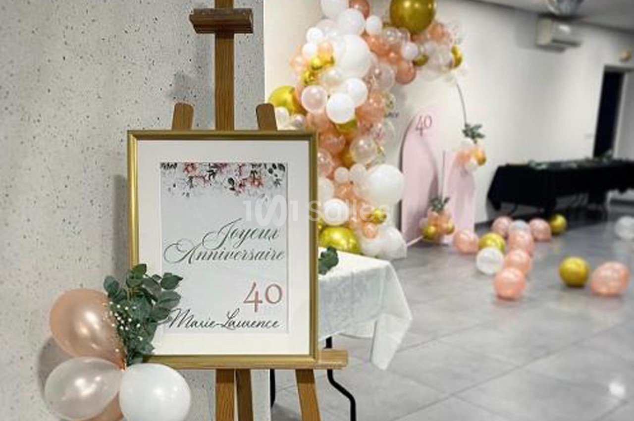 Panneau ’Joyeux Anniversaire 40 Marie-Laurence’ sur un chevalet, décoré de ballons roses, blancs et dorés en arrière-plan.