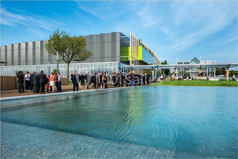 Groupe de personnes rassemblées près d'un bâtiment moderne avec une façade colorée, devant un bassin d'eau.