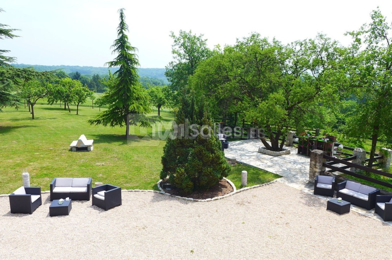 Espace extérieur avec mobilier de jardin, allée pavée, arbres et pelouse verdoyante en arrière-plan.