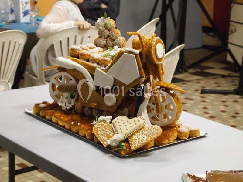 Pièce montée en forme de moto réalisée en pâte à choux et nougatine, posée sur une table dans une salle.