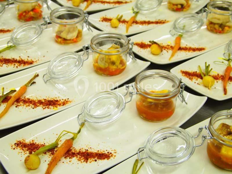 Assiettes dressées avec des bocaux de légumes marinés, carottes miniatures et poudre d'épices rouges.