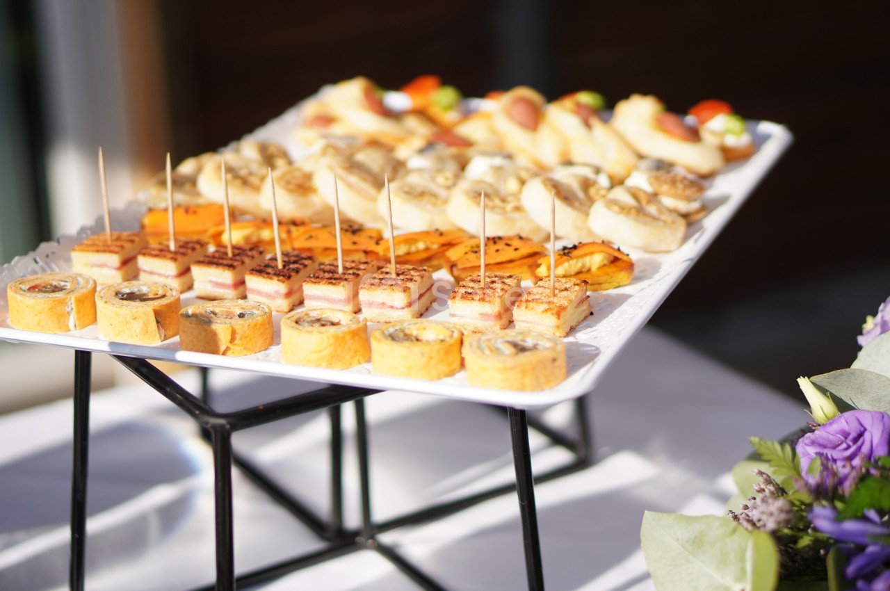 Plateau de canapés variés disposés sur une table, éclairés par la lumière naturelle.