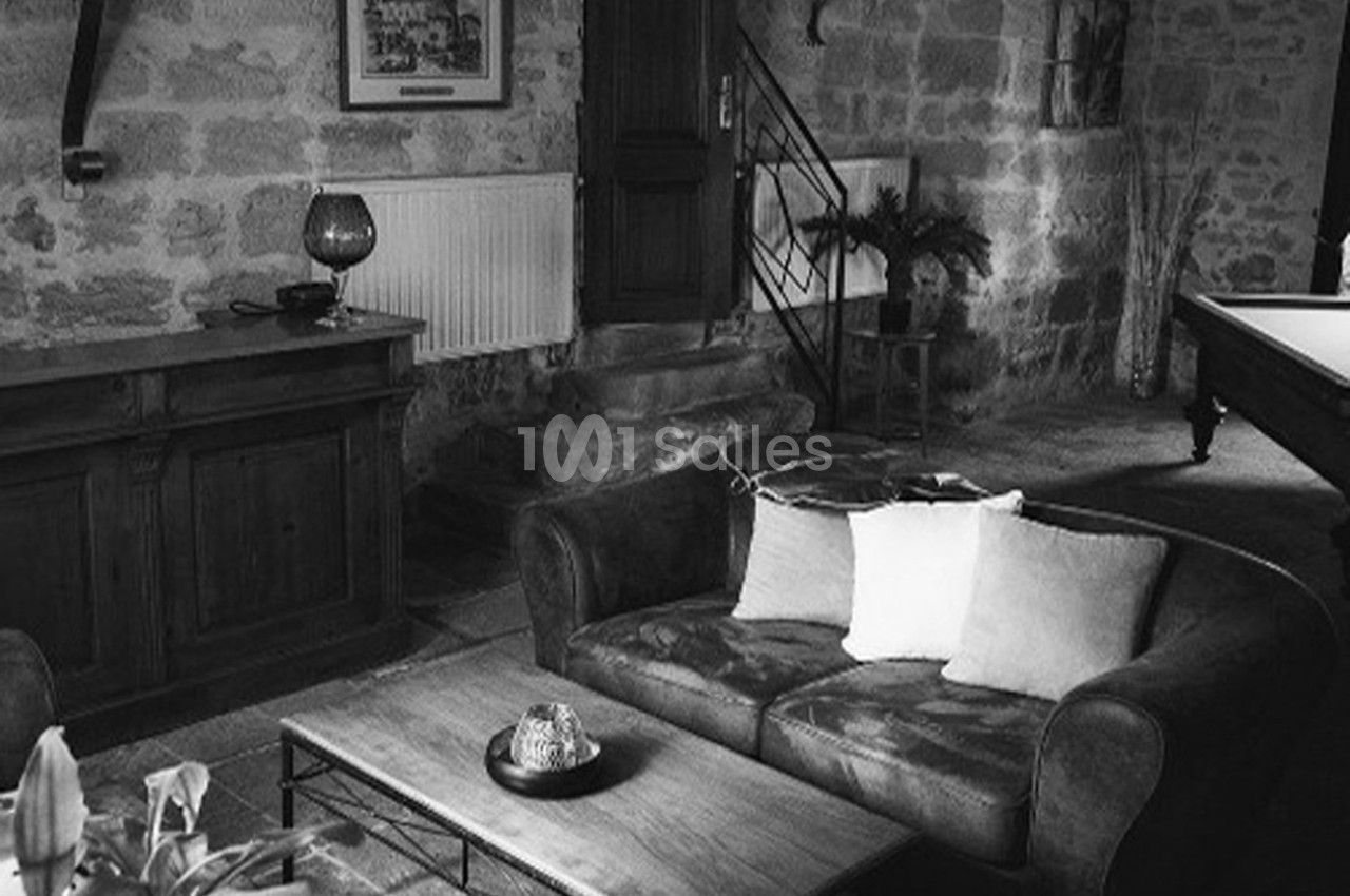 Salon rustique en noir et blanc avec canapé, table basse, meuble en bois et mur en pierre apparente.