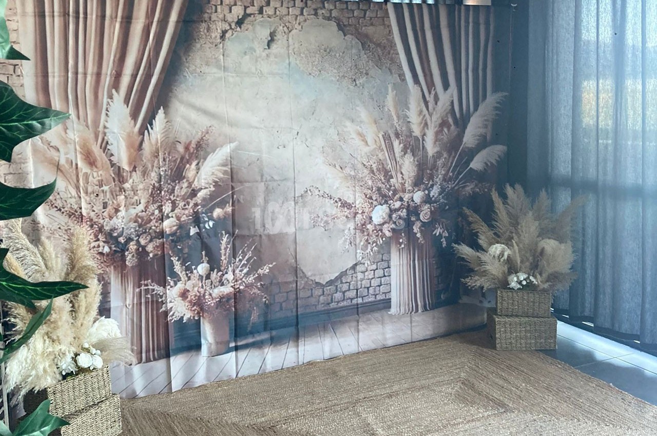 Décor avec fond en briques, fleurs séchées et plantes dans des paniers, éclairé par une lumière naturelle.