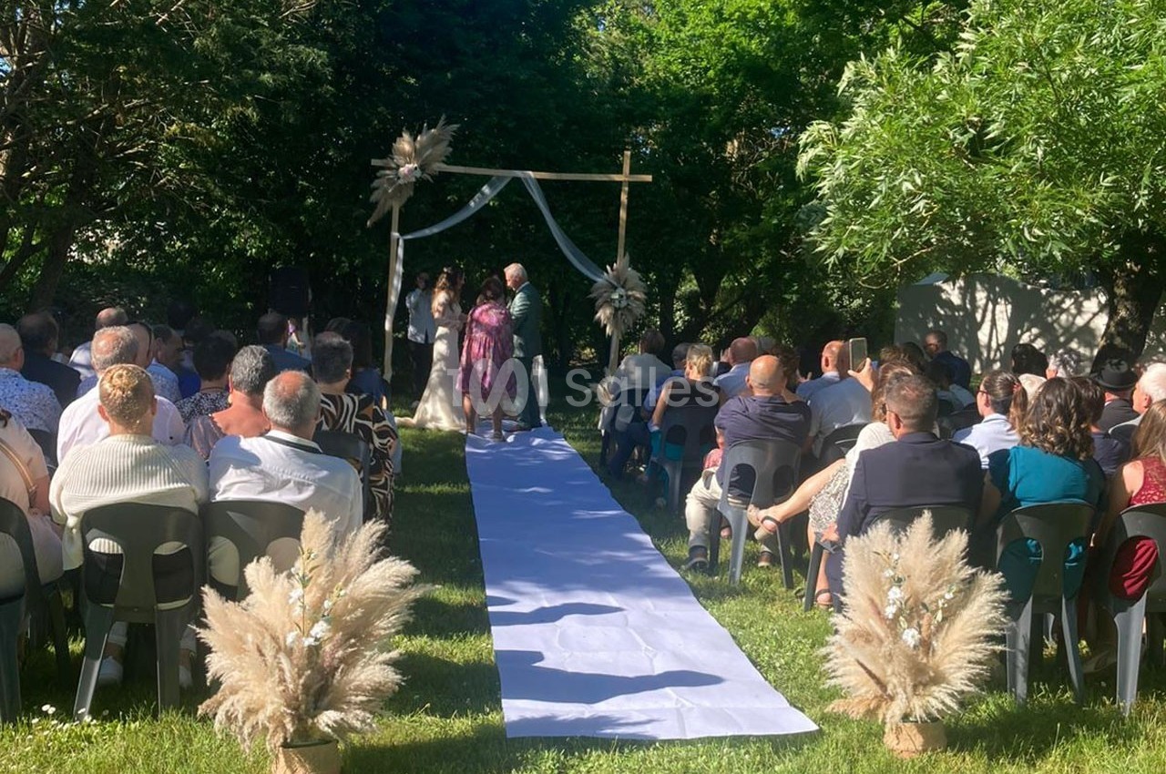 Cérémonie de mariage en plein air avec des invités assis, une arche décorée et un couple devant l'officiant.