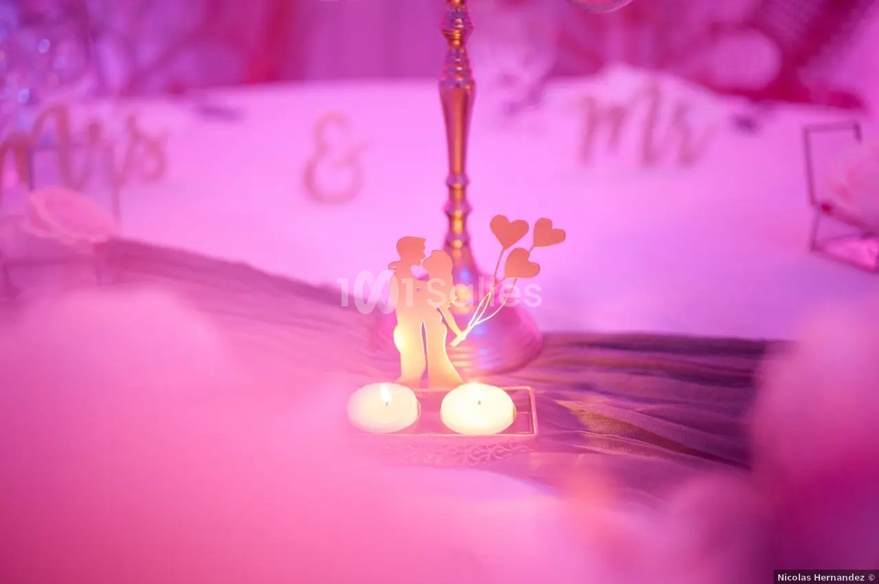 Décoration romantique avec une silhouette de couple, deux bougies allumées et un fond rose flou.