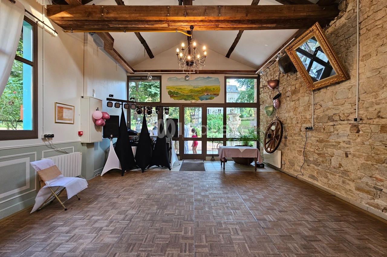 Salle lumineuse avec parquet, poutres apparentes, murs en pierre, décorations festives et grande baie vitrée donnant sur l…