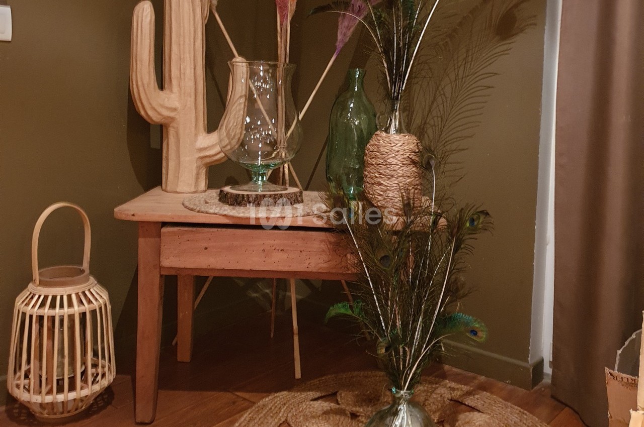 Décoration intérieure avec table en bois, cactus en bois, vases décoratifs et panier en osier sur un sol en parquet.