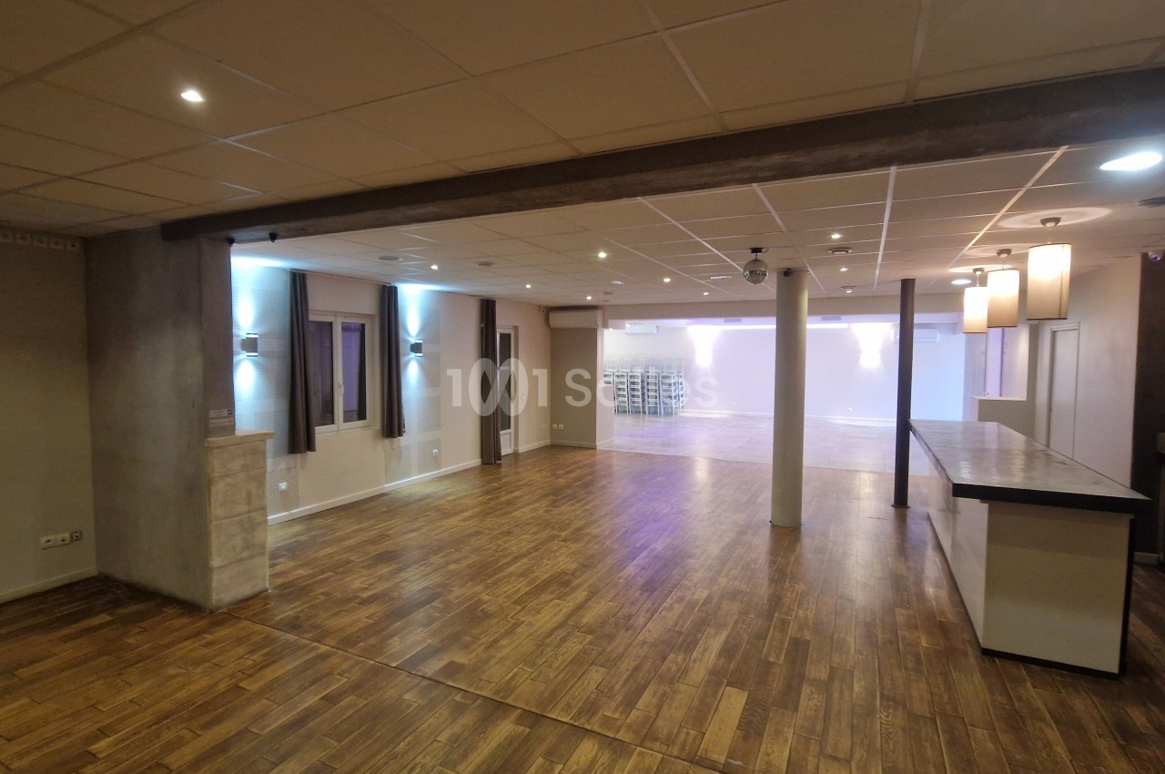 Salle intérieure vide avec sol en parquet, colonnes, éclairage LED et baies vitrées.