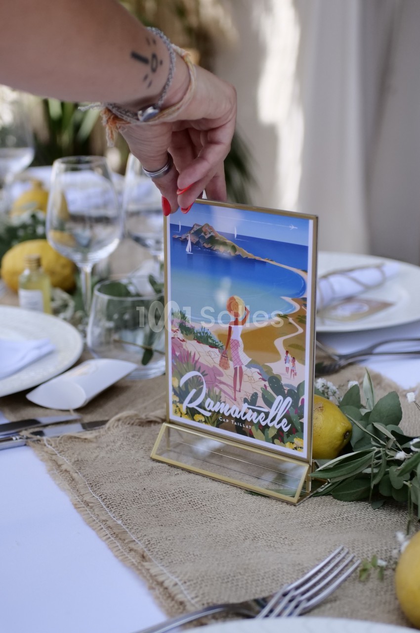 Carte illustrée de Ramatuelle placée sur une table décorée avec des citrons, des verres et une nappe en toile de jute.