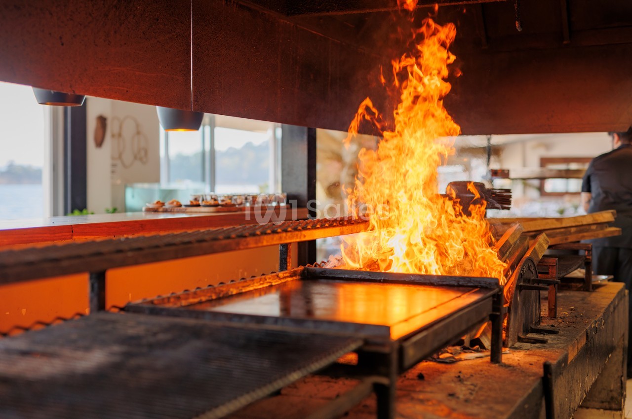 Foyer ouvert avec flammes actives dans cuisine ouverte - vue sur mer en arrière-plan.