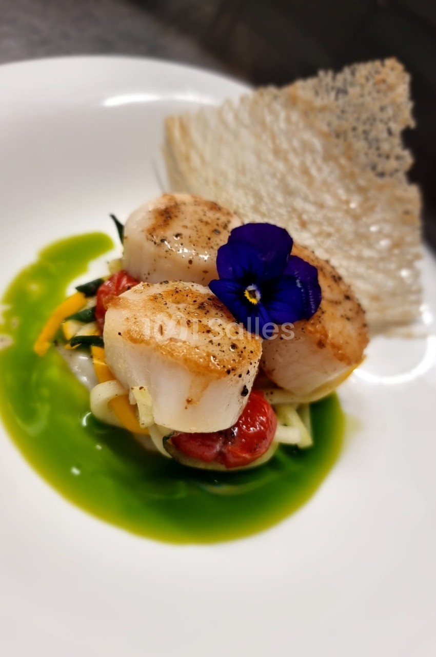 Noix de Saint-Jacques poêlées sur lit de légumes, sauce verte et décorées d'une fleur comestible, accompagnées d'une tuile…