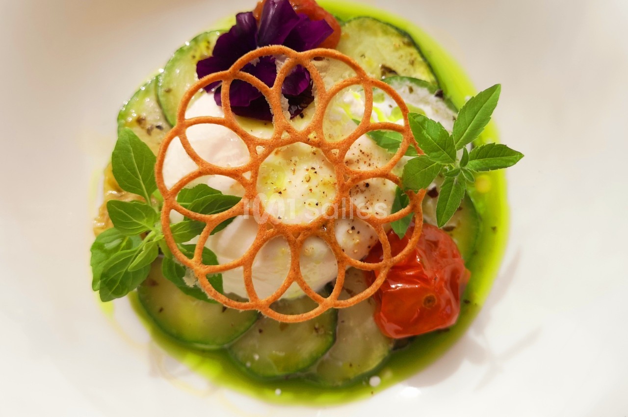 Assiette gastronomique avec courgettes, tomate, mousse blanche, décoration croustillante et herbes fraîches.