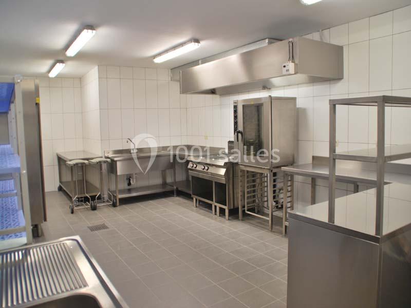 Cuisine professionnelle avec équipements en inox, comprenant un four, des plans de travail et un évier, dans un espace…