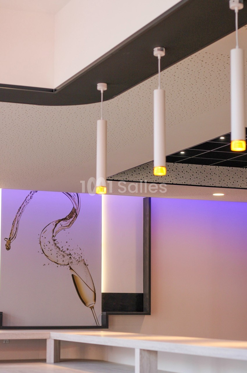 Suspensions lumineuses modernes dans un intérieur avec un mur décoré d'une illustration de verre de champagne.