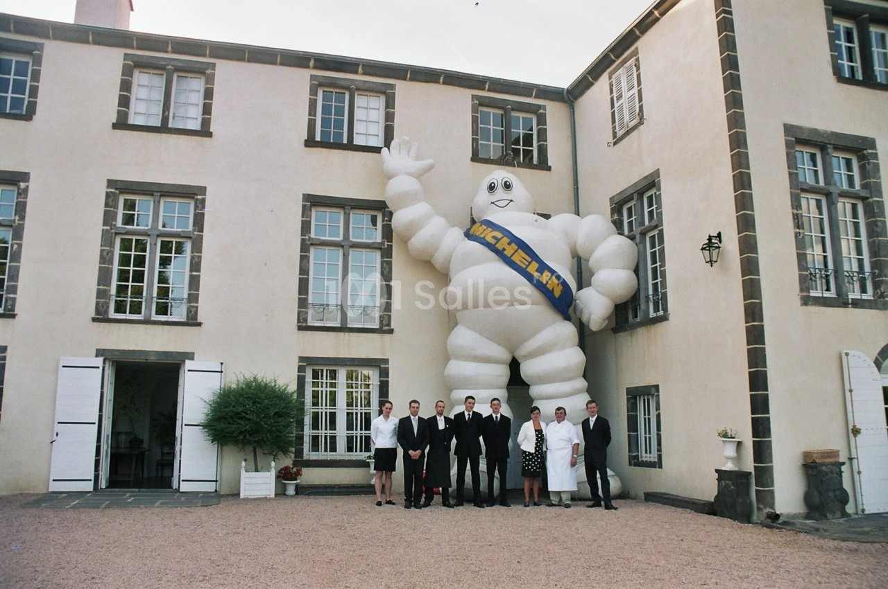 Un groupe de personnes pose devant un grand bâtiment avec une statue gonflable du Bibendum Michelin.
