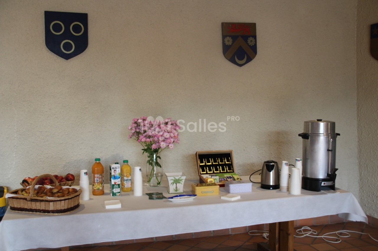 Table avec boissons, viennoiseries, fleurs et machine à café, disposée pour un buffet ou une collation.