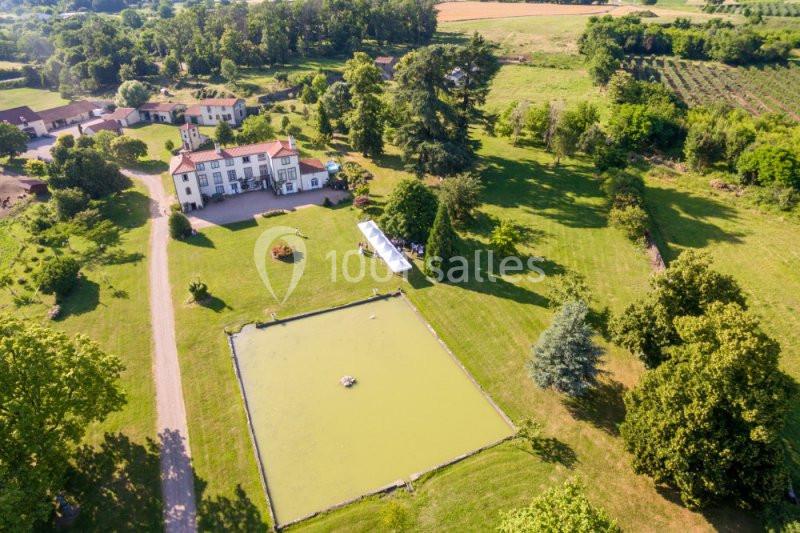Vue aérienne d'une grande propriété avec un étang, une maison principale, des arbres et des champs environnants.