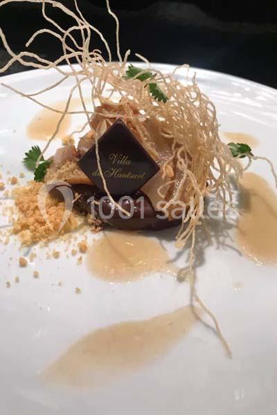 Dessert raffiné avec chocolat, croustillant de nouilles, crumble et sauce caramel sur une assiette blanche.