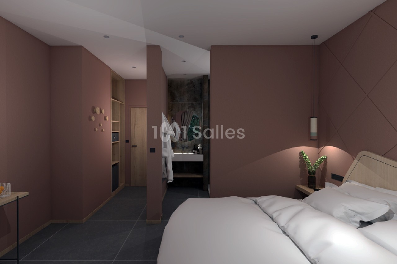 Chambre moderne avec murs roses, lit double, éclairage doux, et salle de bain attenante visible en arrière-plan.