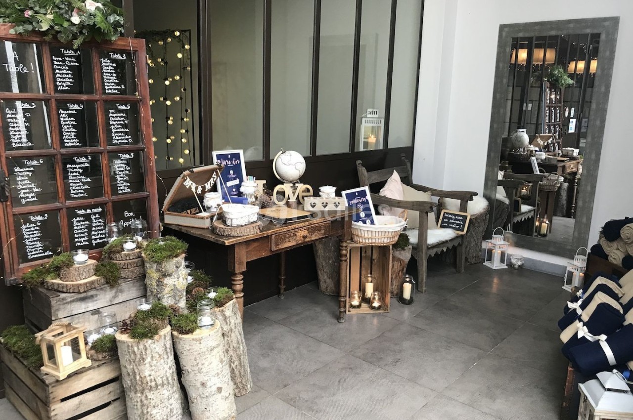 Décoration de mariage avec plan de table sur une fenêtre ancienne, guirlandes lumineuses et éléments rustiques en bois.