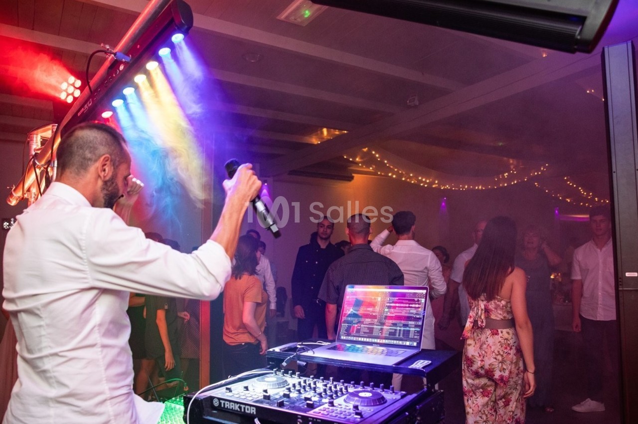 Un DJ anime une soirée dansante avec des lumières colorées et des invités sur la piste de danse.