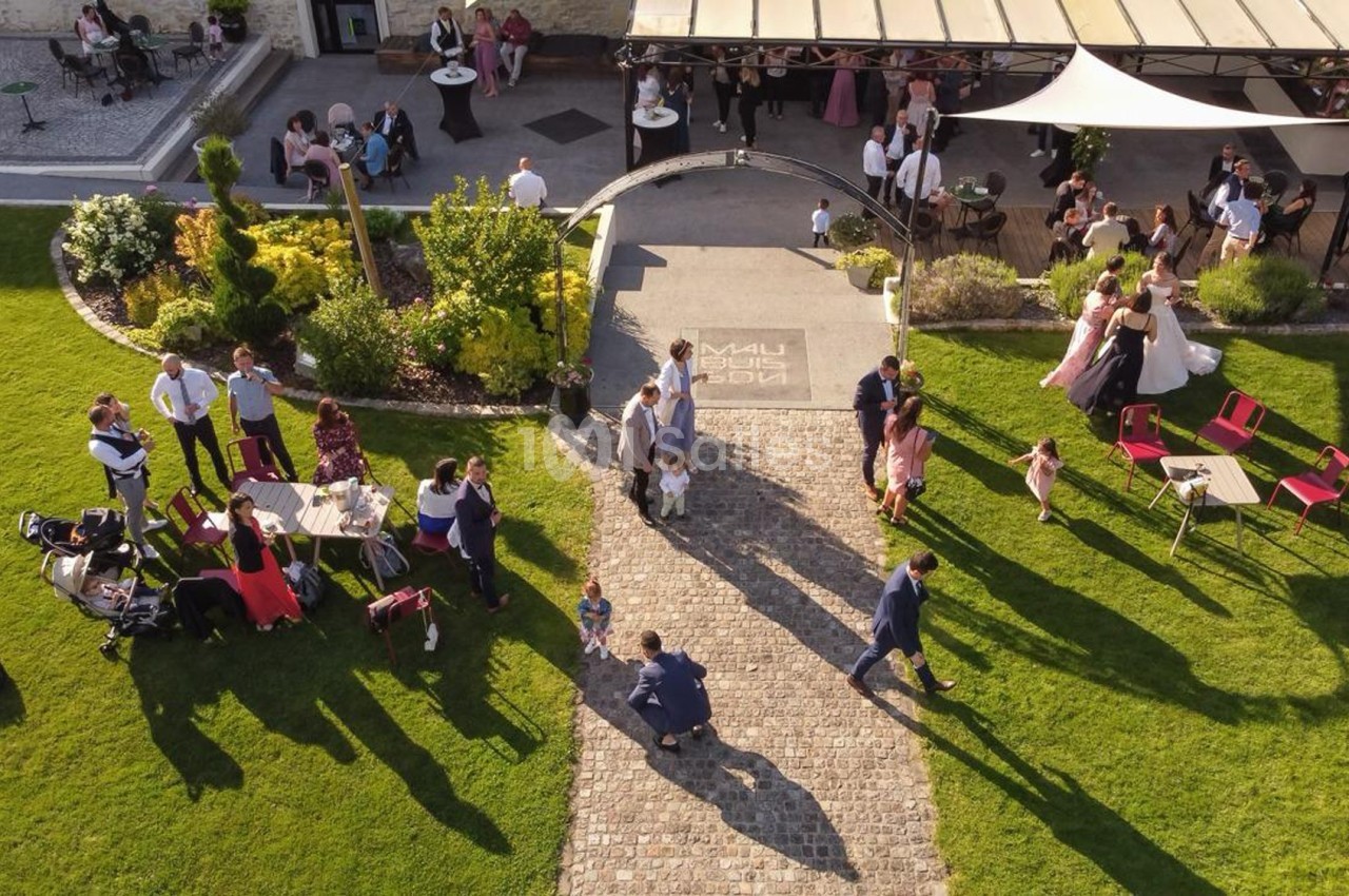 Vue aérienne d'un jardin avec des invités rassemblés lors d'un événement en plein air près d'une terrasse aménagée.
